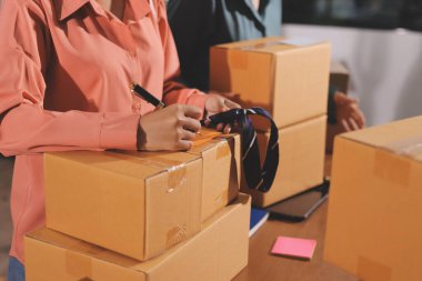 Girişim KOBİ küçük işletme girişimcisi önlük giyen Asyalı kadın dizüstü bilgisayar ve kutu kullanarak çevrimiçi müşterilere, çevrimiçi sme iş fikirlerine satış hazırlamak için siparişleri alır ve gözden geçirir.