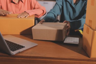 Girişim KOBİ küçük işletme girişimcisi önlük giyen Asyalı kadın dizüstü bilgisayar ve kutu kullanarak çevrimiçi müşterilere, çevrimiçi sme iş fikirlerine satış hazırlamak için siparişleri alır ve gözden geçirir.