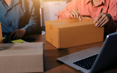 Girişim KOBİ küçük işletme girişimcisi önlük giyen Asyalı kadın dizüstü bilgisayar ve kutu kullanarak çevrimiçi müşterilere, çevrimiçi sme iş fikirlerine satış hazırlamak için siparişleri alır ve gözden geçirir.