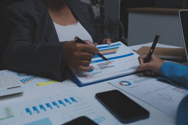 Ofiste çalışan denetçi ve muhasebeci ekibi mali verileri ve muhasebe kayıtlarını hesap makinesiyle analiz ediyor. Muhasebe şirketi kârlı nakit akışı için finansman ve vergilendirme planlaması sağlıyor.