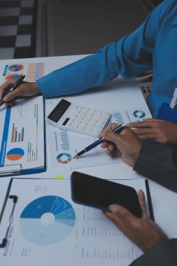 Ofiste çalışan denetçi ve muhasebeci ekibi mali verileri ve muhasebe kayıtlarını hesap makinesiyle analiz ediyor. Muhasebe şirketi kârlı nakit akışı için finansman ve vergilendirme planlaması sağlıyor.