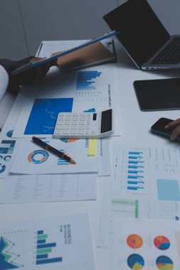 Ofiste çalışan denetçi ve muhasebeci ekibi mali verileri ve muhasebe kayıtlarını hesap makinesiyle analiz ediyor. Muhasebe şirketi kârlı nakit akışı için finansman ve vergilendirme planlaması sağlıyor.