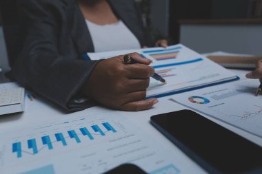 Ofiste çalışan denetçi ve muhasebeci ekibi mali verileri ve muhasebe kayıtlarını hesap makinesiyle analiz ediyor. Muhasebe şirketi kârlı nakit akışı için finansman ve vergilendirme planlaması sağlıyor.