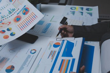 Ofiste çalışan denetçi ve muhasebeci ekibi mali verileri ve muhasebe kayıtlarını hesap makinesiyle analiz ediyor. Muhasebe şirketi kârlı nakit akışı için finansman ve vergilendirme planlaması sağlıyor.