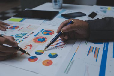 Ofiste çalışan denetçi ve muhasebeci ekibi mali verileri ve muhasebe kayıtlarını hesap makinesiyle analiz ediyor. Muhasebe şirketi kârlı nakit akışı için finansman ve vergilendirme planlaması sağlıyor.