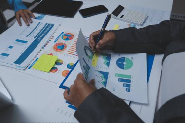 Ofiste çalışan denetçi ve muhasebeci ekibi mali verileri ve muhasebe kayıtlarını hesap makinesiyle analiz ediyor. Muhasebe şirketi kârlı nakit akışı için finansman ve vergilendirme planlaması sağlıyor.