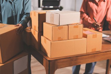 Girişim KOBİ küçük işletme girişimcisi önlük giyen Asyalı kadın dizüstü bilgisayar ve kutu kullanarak çevrimiçi müşterilere, çevrimiçi sme iş fikirlerine satış hazırlamak için siparişleri alır ve gözden geçirir.