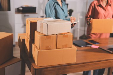 Girişim KOBİ küçük işletme girişimcisi önlük giyen Asyalı kadın dizüstü bilgisayar ve kutu kullanarak çevrimiçi müşterilere, çevrimiçi sme iş fikirlerine satış hazırlamak için siparişleri alır ve gözden geçirir.