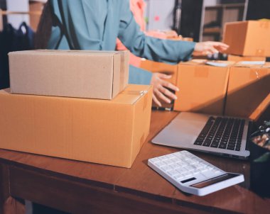 Girişim KOBİ küçük işletme girişimcisi önlük giyen Asyalı kadın dizüstü bilgisayar ve kutu kullanarak çevrimiçi müşterilere, çevrimiçi sme iş fikirlerine satış hazırlamak için siparişleri alır ve gözden geçirir.