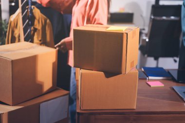 Girişim KOBİ küçük işletme girişimcisi önlük giyen Asyalı kadın dizüstü bilgisayar ve kutu kullanarak çevrimiçi müşterilere, çevrimiçi sme iş fikirlerine satış hazırlamak için siparişleri alır ve gözden geçirir.