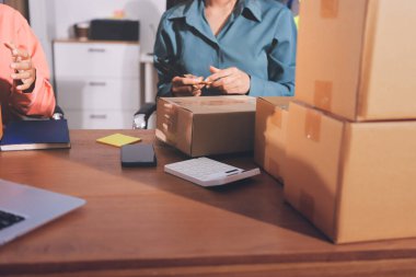 Girişim KOBİ küçük işletme girişimcisi önlük giyen Asyalı kadın dizüstü bilgisayar ve kutu kullanarak çevrimiçi müşterilere, çevrimiçi sme iş fikirlerine satış hazırlamak için siparişleri alır ve gözden geçirir.