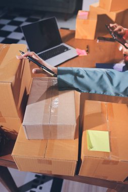 Girişim KOBİ küçük işletme girişimcisi önlük giyen Asyalı kadın dizüstü bilgisayar ve kutu kullanarak çevrimiçi müşterilere, çevrimiçi sme iş fikirlerine satış hazırlamak için siparişleri alır ve gözden geçirir.