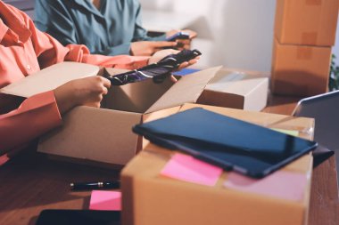 Girişim KOBİ küçük işletme girişimcisi önlük giyen Asyalı kadın dizüstü bilgisayar ve kutu kullanarak çevrimiçi müşterilere, çevrimiçi sme iş fikirlerine satış hazırlamak için siparişleri alır ve gözden geçirir.