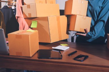 Girişim KOBİ küçük işletme girişimcisi önlük giyen Asyalı kadın dizüstü bilgisayar ve kutu kullanarak çevrimiçi müşterilere, çevrimiçi sme iş fikirlerine satış hazırlamak için siparişleri alır ve gözden geçirir.