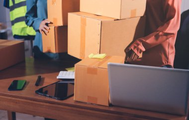 Girişim KOBİ küçük işletme girişimcisi önlük giyen Asyalı kadın dizüstü bilgisayar ve kutu kullanarak çevrimiçi müşterilere, çevrimiçi sme iş fikirlerine satış hazırlamak için siparişleri alır ve gözden geçirir.