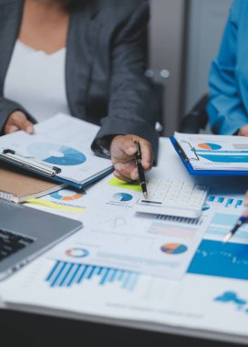 Ofiste çalışan denetçi ve muhasebeci ekibi mali verileri ve muhasebe kayıtlarını hesap makinesiyle analiz ediyor. Muhasebe şirketi kârlı nakit akışı için finansman ve vergilendirme planlaması sağlıyor.