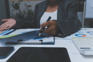 Ofiste çalışan denetçi ve muhasebeci ekibi mali verileri ve muhasebe kayıtlarını hesap makinesiyle analiz ediyor. Muhasebe şirketi kârlı nakit akışı için finansman ve vergilendirme planlaması sağlıyor.