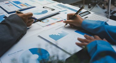 Ofiste çalışan denetçi ve muhasebeci ekibi mali verileri ve muhasebe kayıtlarını hesap makinesiyle analiz ediyor. Muhasebe şirketi kârlı nakit akışı için finansman ve vergilendirme planlaması sağlıyor.