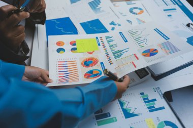 Ofiste çalışan denetçi ve muhasebeci ekibi mali verileri ve muhasebe kayıtlarını hesap makinesiyle analiz ediyor. Muhasebe şirketi kârlı nakit akışı için finansman ve vergilendirme planlaması sağlıyor.