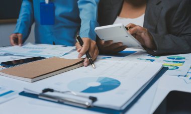 Ofiste çalışan denetçi ve muhasebeci ekibi mali verileri ve muhasebe kayıtlarını hesap makinesiyle analiz ediyor. Muhasebe şirketi kârlı nakit akışı için finansman ve vergilendirme planlaması sağlıyor.