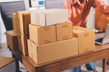 Girişim KOBİ küçük işletme girişimcisi önlük giyen Asyalı kadın dizüstü bilgisayar ve kutu kullanarak çevrimiçi müşterilere, çevrimiçi sme iş fikirlerine satış hazırlamak için siparişleri alır ve gözden geçirir.