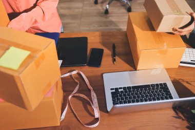 Girişim KOBİ küçük işletme girişimcisi önlük giyen Asyalı kadın dizüstü bilgisayar ve kutu kullanarak çevrimiçi müşterilere, çevrimiçi sme iş fikirlerine satış hazırlamak için siparişleri alır ve gözden geçirir.