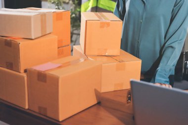 Girişim KOBİ küçük işletme girişimcisi önlük giyen Asyalı kadın dizüstü bilgisayar ve kutu kullanarak çevrimiçi müşterilere, çevrimiçi sme iş fikirlerine satış hazırlamak için siparişleri alır ve gözden geçirir.