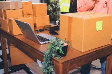 Girişim KOBİ küçük işletme girişimcisi önlük giyen Asyalı kadın dizüstü bilgisayar ve kutu kullanarak çevrimiçi müşterilere, çevrimiçi sme iş fikirlerine satış hazırlamak için siparişleri alır ve gözden geçirir.