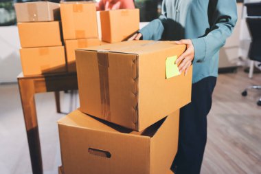 Girişim KOBİ küçük işletme girişimcisi önlük giyen Asyalı kadın dizüstü bilgisayar ve kutu kullanarak çevrimiçi müşterilere, çevrimiçi sme iş fikirlerine satış hazırlamak için siparişleri alır ve gözden geçirir.