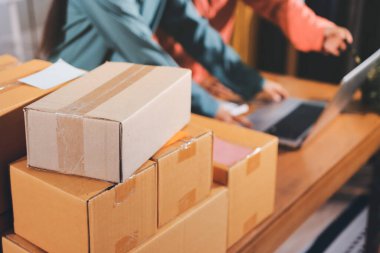 Girişim KOBİ küçük işletme girişimcisi önlük giyen Asyalı kadın dizüstü bilgisayar ve kutu kullanarak çevrimiçi müşterilere, çevrimiçi sme iş fikirlerine satış hazırlamak için siparişleri alır ve gözden geçirir.