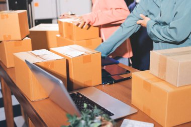 Girişim KOBİ küçük işletme girişimcisi önlük giyen Asyalı kadın dizüstü bilgisayar ve kutu kullanarak çevrimiçi müşterilere, çevrimiçi sme iş fikirlerine satış hazırlamak için siparişleri alır ve gözden geçirir.