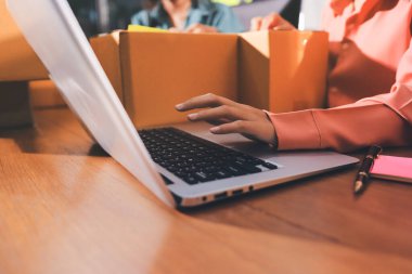 Girişim KOBİ küçük işletme girişimcisi önlük giyen Asyalı kadın dizüstü bilgisayar ve kutu kullanarak çevrimiçi müşterilere, çevrimiçi sme iş fikirlerine satış hazırlamak için siparişleri alır ve gözden geçirir.