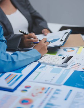 Ofiste çalışan denetçi ve muhasebeci ekibi mali verileri ve muhasebe kayıtlarını hesap makinesiyle analiz ediyor. Muhasebe şirketi kârlı nakit akışı için finansman ve vergilendirme planlaması sağlıyor.