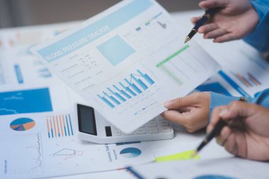 Ofiste çalışan denetçi ve muhasebeci ekibi mali verileri ve muhasebe kayıtlarını hesap makinesiyle analiz ediyor. Muhasebe şirketi kârlı nakit akışı için finansman ve vergilendirme planlaması sağlıyor.