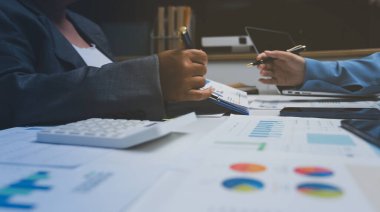 Ofiste çalışan denetçi ve muhasebeci ekibi mali verileri ve muhasebe kayıtlarını hesap makinesiyle analiz ediyor. Muhasebe şirketi kârlı nakit akışı için finansman ve vergilendirme planlaması sağlıyor.