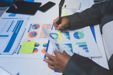 Ofiste çalışan denetçi ve muhasebeci ekibi mali verileri ve muhasebe kayıtlarını hesap makinesiyle analiz ediyor. Muhasebe şirketi kârlı nakit akışı için finansman ve vergilendirme planlaması sağlıyor.