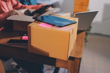 Girişim KOBİ küçük işletme girişimcisi önlük giyen Asyalı kadın dizüstü bilgisayar ve kutu kullanarak çevrimiçi müşterilere, çevrimiçi sme iş fikirlerine satış hazırlamak için siparişleri alır ve gözden geçirir.