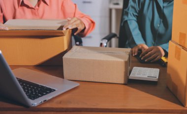 Girişim KOBİ küçük işletme girişimcisi önlük giyen Asyalı kadın dizüstü bilgisayar ve kutu kullanarak çevrimiçi müşterilere, çevrimiçi sme iş fikirlerine satış hazırlamak için siparişleri alır ve gözden geçirir.