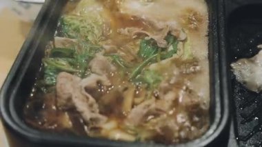 Shabu Shabu veya Sukiyaki veya güveç, domuz restoranında Japon yemekleri yemek çubukları, kullanarak tutan el