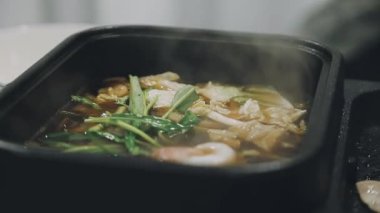 Shabu Shabu veya Sukiyaki veya güveç, domuz restoranında Japon yemekleri yemek çubukları, kullanarak tutan el