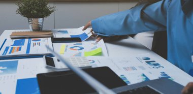 Ofiste çalışan denetçi ve muhasebeci ekibi mali verileri ve muhasebe kayıtlarını hesap makinesiyle analiz ediyor. Muhasebe şirketi kârlı nakit akışı için finansman ve vergilendirme planlaması sağlıyor.