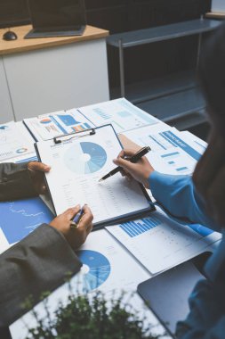 Ofiste çalışan denetçi ve muhasebeci ekibi mali verileri ve muhasebe kayıtlarını hesap makinesiyle analiz ediyor. Muhasebe şirketi kârlı nakit akışı için finansman ve vergilendirme planlaması sağlıyor.