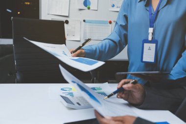 Ofiste çalışan denetçi ve muhasebeci ekibi mali verileri ve muhasebe kayıtlarını hesap makinesiyle analiz ediyor. Muhasebe şirketi kârlı nakit akışı için finansman ve vergilendirme planlaması sağlıyor.