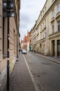 Dar kaldırım taşı caddesi, Krakow 'un Eski Kenti UNESCO' nun Dünya Mirası Alanındaki tarihi binalarla dolu ve kırmızı tuğlalı Gotik kilisesi uzaktan görülebiliyor. Ortaçağdan Rönesans dönemlerine kadar karışık mimari tarzlar.