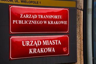 Toplu Taşımacılık Dairesi (Zarzad Transportu Publicznego) ve Wielopole 1 'deki Krakow Belediye Binası ofislerini simgeleyen kırmızı diş minesi kurumsal plaketleri, geleneksel Polonya belediye tabelası