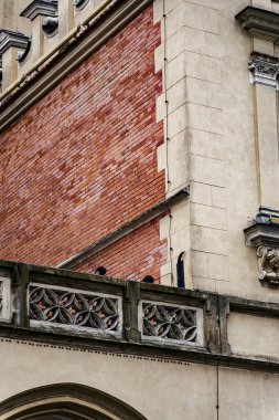 Mimari detay kırmızı kil kiremit kiremit çatı kaplama, rustik quoinlerle krem taş duvarlar ve Polonya 'nın Krakow kentindeki tarihi bina üzerindeki dört katlı folyo panelleri gösteriyor. Rönesans ve Barok dönemi elementleri.