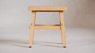 Üç boyutlu minimalist tahta tabure, açılı bacaklar, destek kirişleri ve pürüzsüz bitiş. Mobilya katalogları, ürün görselleştirme, iç tasarım projeleri ve modern dekor sunumları için mükemmel..