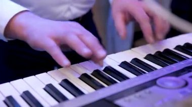 Elektronik piyano çalan bir müzisyenin elleri, bir sentezleyici. Sesleri karıştırıyor. Caz, rock, pop müzik.