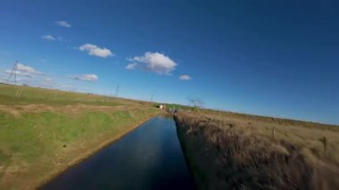 FPV insansız hava aracı, kırsal tarım arazileri ve tarlaların üzerinden uçuyor, sel bankaları ve sulak bataklık bölgeleri, Hughnshire, İngiltere, İngiltere, güneşli bahar günü 