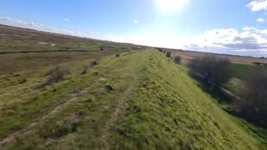 FPV insansız hava aracı, kırsal tarım arazileri ve tarlaların üzerinden uçuyor, sel bankaları ve sulak bataklık bölgeleri, Hughnshire, İngiltere, İngiltere, güneşli bahar günü 